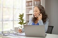 A professional mature Asian female boss is on the phone with a supplier to deal a new contract Royalty Free Stock Photo