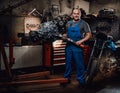 Professional mechanic stands next to the suspended flat engine and naked bike in garage