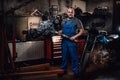 Professional mechanic stands next to the suspended flat engine and naked bike in garage Royalty Free Stock Photo