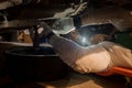 Professional mechanic working underneath a car performing maintenance tasks and repairs in automotive garage workshop Royalty Free Stock Photo