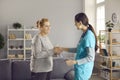 Smiling friendly female doctor nurse greeting handshake senior old lady patient