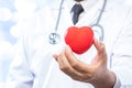 Professional medical doctor holding a red heart ball on blur off