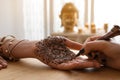 Professional mehndi master making henna tattoo indoors, closeup