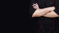 Chef in black jacket standing with arms folded on black background