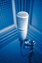 Professional microphone in sound recording studio, blue acoustic foam background