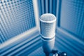 Professional microphone in sound recording studio, blue acoustic foam background