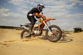 Professional motocross rider driving on sand dune