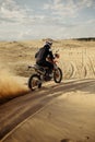 Professional motocross rider driving on sand dune