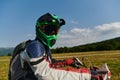 A professional motocross rider, fully geared up with helmet, gloves, and goggles, sitting poised on their motorcycle