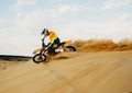 Professional motocross rider sliding down sand hill