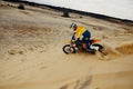 Professional motocross rider sliding down sand hill