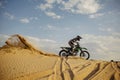 Professional motocross rider sliding down sand hill