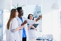 Professional multi ethnic doctors are examining a patient`s X-ray. Two female doctors and one male doctor work together Royalty Free Stock Photo