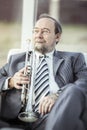 Portrait of a musician with a trumpet sitting in a chair, on the background of the concert hall Royalty Free Stock Photo