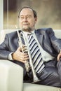 Portrait of a musician with a trumpet sitting in a chair, on the background of the concert hall Royalty Free Stock Photo