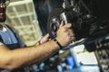 Professional near the car hanging on the lift at the service station make a diagnostics, repair the brakes