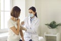 Professional nurse in a medical face mask giving an antiviral vaccine to a young woman Royalty Free Stock Photo