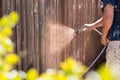 Professional Painter Spraying Yard Fence with Stain