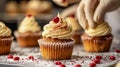 Professional pastry chef hands with white latex gloves decorating cupcakes with cream and red hearts. Royalty Free Stock Photo