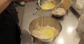 A professional pastry chef woman mixes eggs and adds them to a large bowl