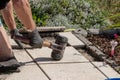 A professional paver worker laying patio slabs in a gravel bed using a professional paving hammer. Equipment from a bricklayer for