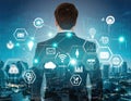 Professional person in suit looking at digital cloud technology over city skyline at night with various icons and data elements Royalty Free Stock Photo