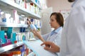 Professional pharmacists near shelves in drugstore