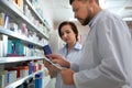 Professional pharmacists near shelves with medicines in drugstore