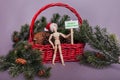 Merry Christmas picket sign jointed doll wearing Santa hat winter scene red basket and pine cones Royalty Free Stock Photo