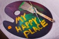 My Happy Place painted on a wooden artist paint palette on canvas backdrop two paintbrushes