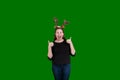 Blond female wearing Christmas reindeer antlers two thumbs up on green screen backdrop