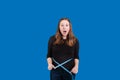 Upset expression on young women face measuring her waist with blue tape measurer