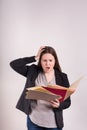 Women in business suite hand on head frustrated with scattered papers and file folders stressed expression