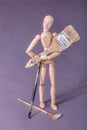 Wooden manikin doll standing holding large paintbrush
