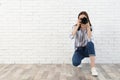 Professional photographer taking picture near white brick wall Royalty Free Stock Photo