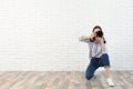 Professional photographer taking picture near white brick wall Royalty Free Stock Photo