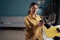 Professional photographer woman holding photo camera posing smiling to camera sitting in home photo studio. Lady taking Royalty Free Stock Photo