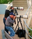 Professional photographers take photos with big cameras.