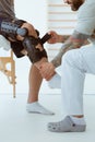 Professional physiotherapist helps the patient to put on an orthosis for the first time