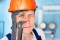 Professional plumber in helmet looks directly into camera through large adjustable wrench. Large portrait of real worker Royalty Free Stock Photo