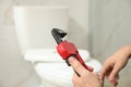 Professional plumber holding pipe wrench near toilet bowl in bathroom Royalty Free Stock Photo
