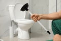 Professional plumber holding plunger near toilet bowl in bathroom Royalty Free Stock Photo
