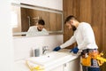 Professional plumber, male worker in uniform installing sink and water pipe in new apartment