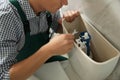 Professional plumber repairing toilet in bathroom Royalty Free Stock Photo