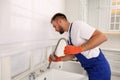 Professional plumber repairing water tap in kitchen Royalty Free Stock Photo