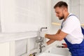 Professional plumber repairing water tap in kitchen Royalty Free Stock Photo