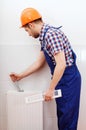 Professional plumber repairing white radiator