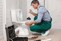 Professional plumber unclogging drain of toilet bowl