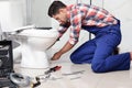 Professional plumber working with toilet bowl in bathroom