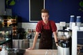 Professional portrait of young trained barista behind a bar counter in coffee shop. Small business, food and drink business